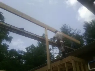 Carpenter setting a ridge beam over a new addition frame — Ice Dam Removal by Roofing Brothers in Gold Hill