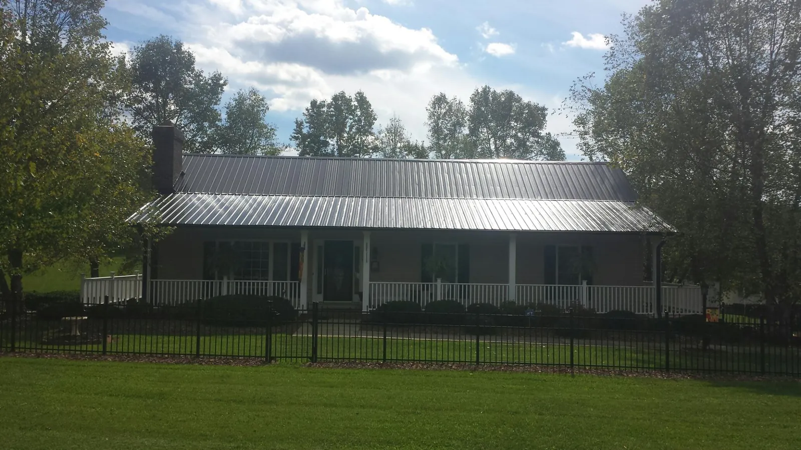 Gray metal roof on a brick ranch with a full width front porch — Gutter Guard Installation work by our crew in Gold Hill