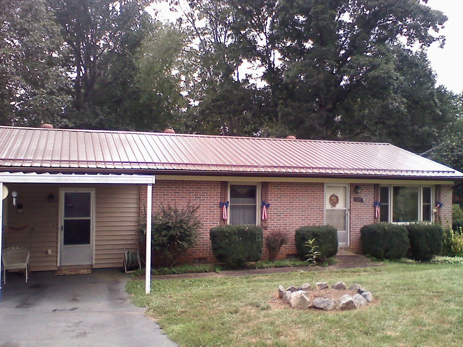 Bronze metal roof and carport on a brick ranch home — Roof Repair work by our crew in Gold Hill