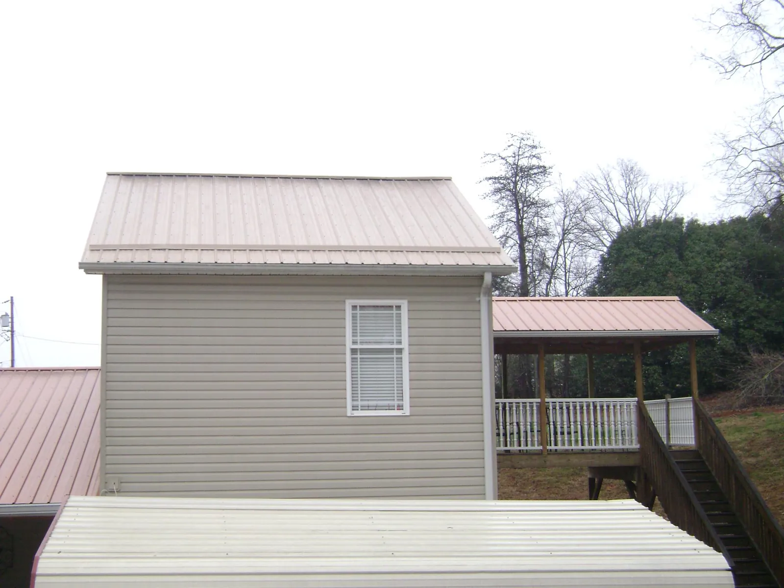Tan metal roofs on a two story addition and attached porch, from a Roof Replacement job in Gold Hill