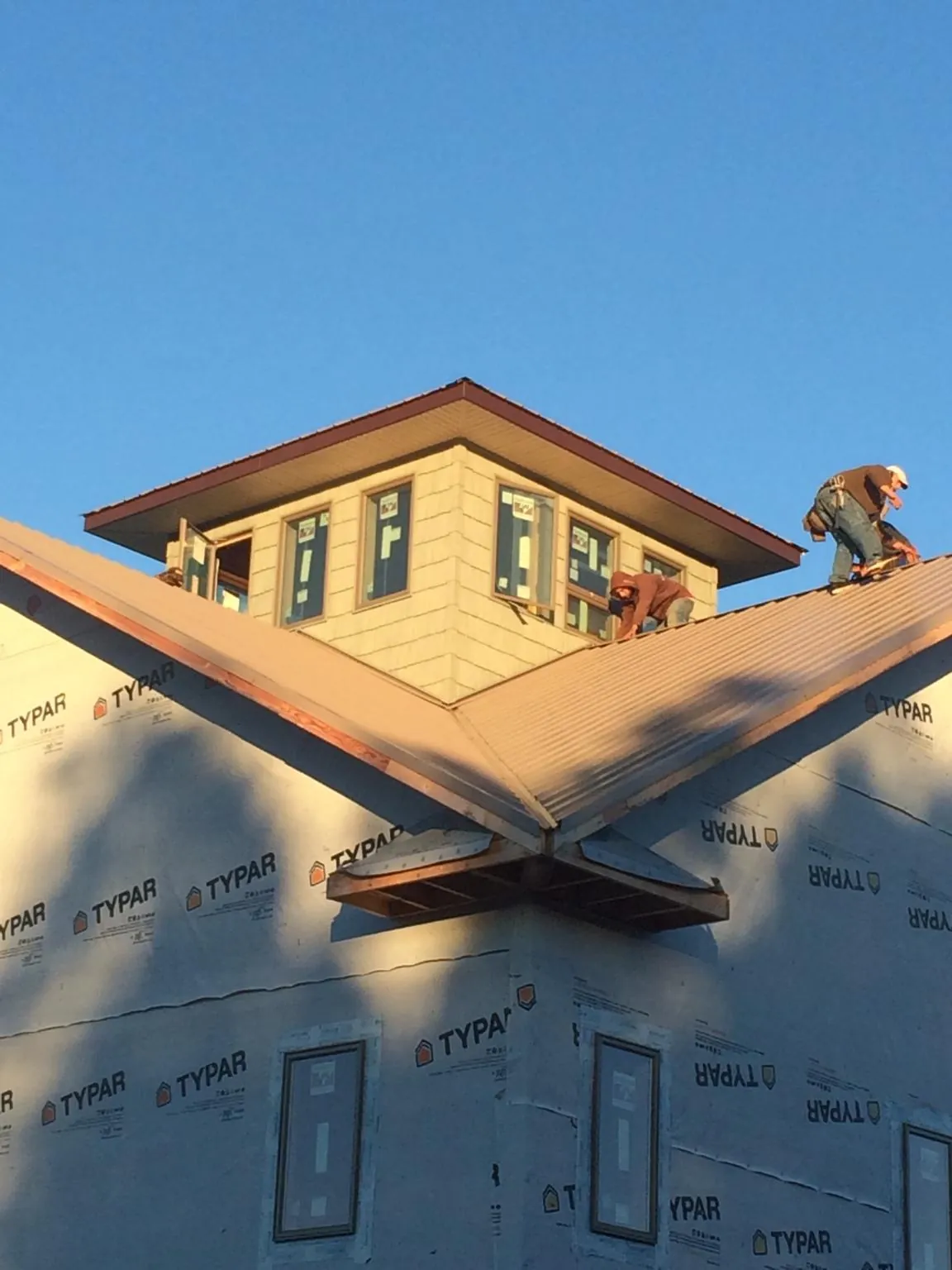 Roofers working around a rooftop cupola on a new metal roof at sunset — Roof Waterproofing in Gold Hill by Roofing Brothers